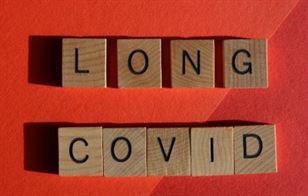 Long Covid spelt out with wooden blocks on red background